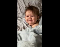 Little baby in bed waking up buried in blanket good morning