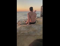 shirtless man sit blows kiss sunset beach