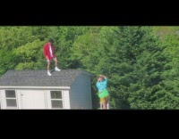Guy stands on shed roof in backyard 