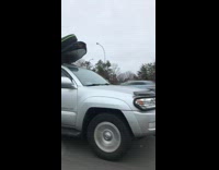 Silver Car Drives With Surfboard On Top of Car