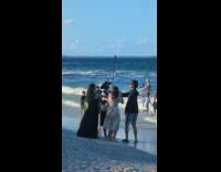 Four people on beach holds selfie stick