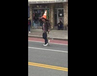 Guy crosses street with traffic cone on head 
