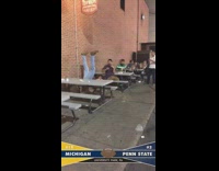 Michigan vs penn state guy tries to jump on table ripped jeans red shirt
