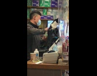 Cashier pets cat standing up by register 