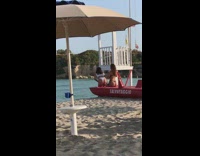 Two bikini girls sit red boat sand 