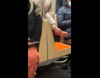 Man scratches barefoot inside the subway train