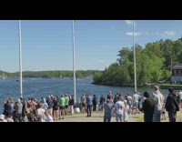 USS Warship sails out while crowd of people watches
