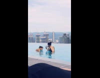 Girl splashes water on friend infinity pool 