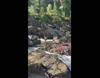 3 guys pose in river with waterfall and rocks 