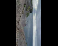 Woman in jacket sit and pose on the cliff