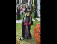 Green witch decoration dancing in front of house