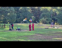 Two people wearing jumpsuits and holding balloons film video 
