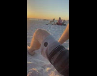Woman in bikini bends over at the beach