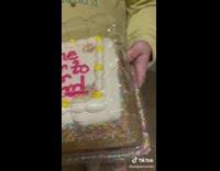 Guy hands friend a cake with dark birthday message