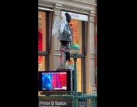 Man on costume stands at subway billboard