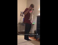 Kitten climbs up man's shirt while he stands and eats dinner