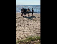4 men carry jet ski on sand 