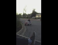 Guy rides in pink toy car behind truck