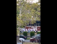 Man in white top dances on the yard of a frat house