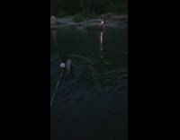 Two women tiktok dance in front of the rock at the river