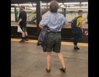Guy in blue floral shirt green shorts dances by himself in subway station