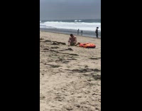 man on beach next to orange raft has shake weight