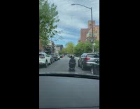 Person riding electrical wheelchair on road blocking car