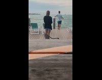 Guy holding drink poses on pier ocean