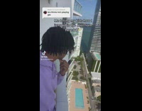 Guy purple hoodie looking off balcony of apartment 