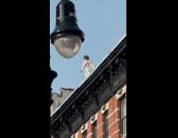 Collab WINY - Person in a white dress walks on rooftop 