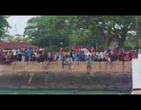 Locals watch man dive flip at pier