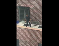Guy stretches his arms outside on balcony