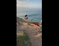Man black shirt sit between dogs ocean