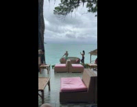 Collab IITW - Woman green dress poses on wooden couch with pink cushion 