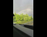 Rainbow arc on a cloudy day seen from the road trip