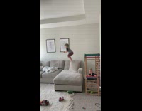 Little kid boy jumps onto grey couch 