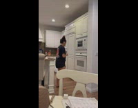 Girl wearing black shirt dances by oven 