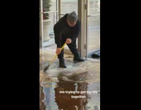 Man Sweeps Water Outside from Flooded Lobby