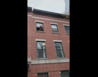 Girl lowers brown bag from apartment window 