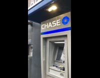 Pigeon sitting down on a broken down chase ATM machine 

