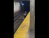 Man walk on train track pick up nickel