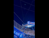 Man tightens chain while fair ride is ongoing 