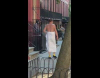 Guy holds white sheet around waist sidewalk 