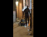 Guy walking balloon dog with suitcase