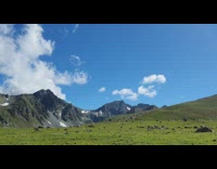 Time lapse white clouds grey mountain grass 