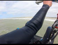 Blue wetsuit guy kitesurfs across ocean water 