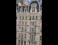 Person sits on windowsill on side of building 