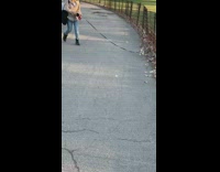 Woman walks her cat on leash at park