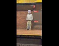 Man stands on train platform head inside box