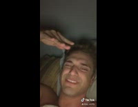 Shirtless guy in bed laughing shadow puppets